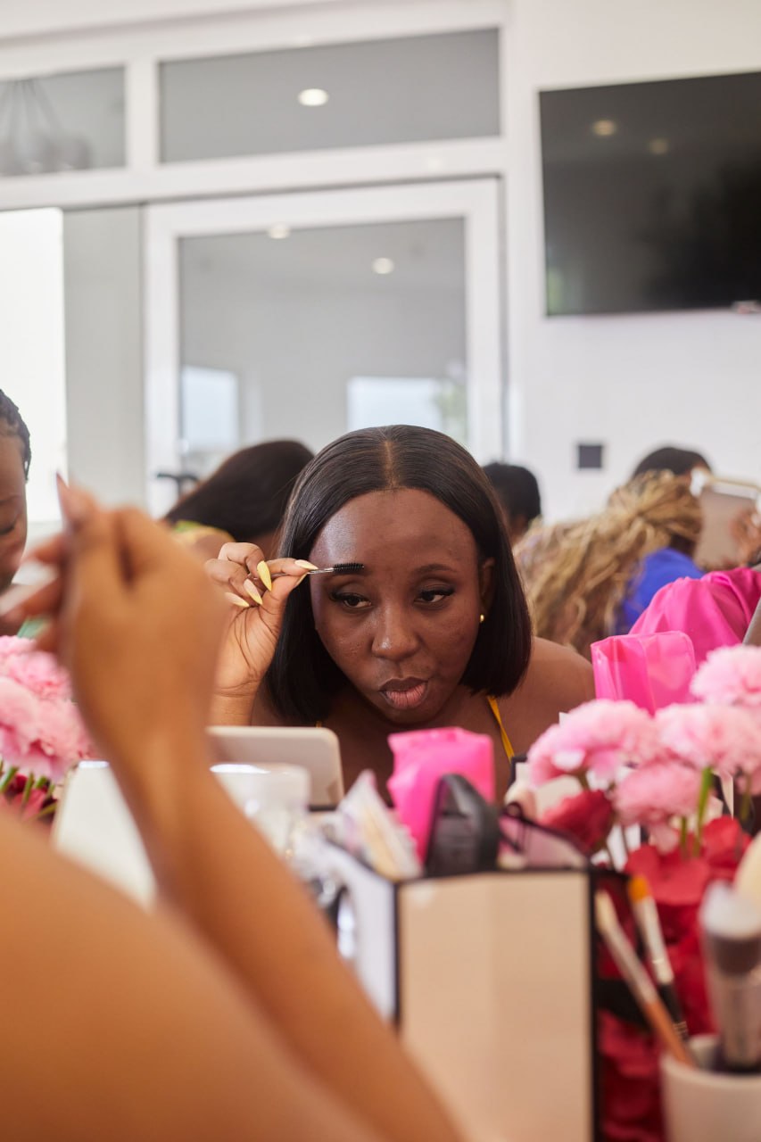 An attendee carefully brushing her brows surrounded by pink florals