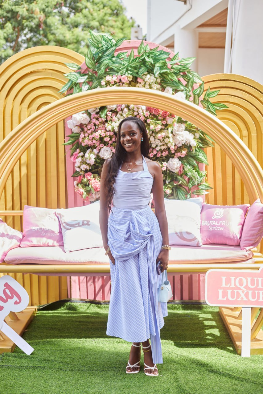 An attendee in a blue dress posing in front of the Liquid Luxury floral arch