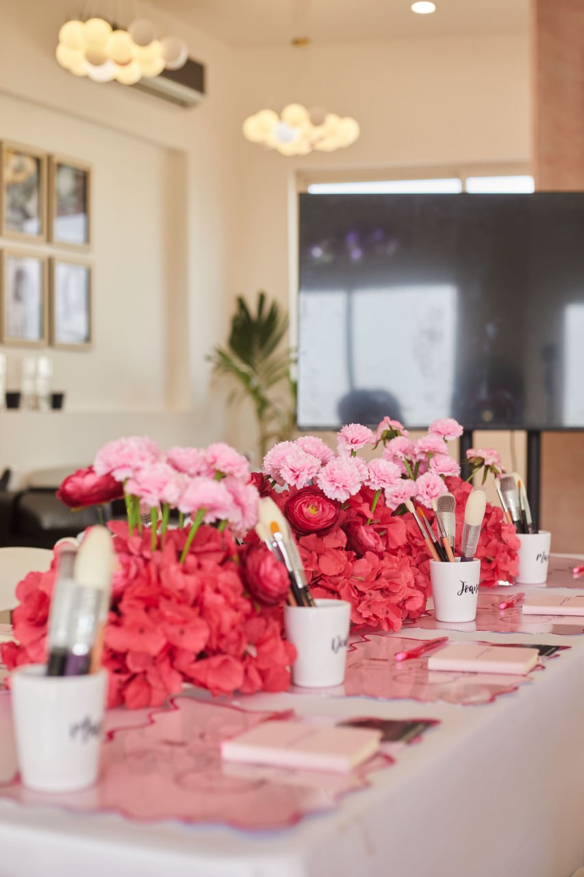 Close-up of brushes in personalised cups among red and pink florals