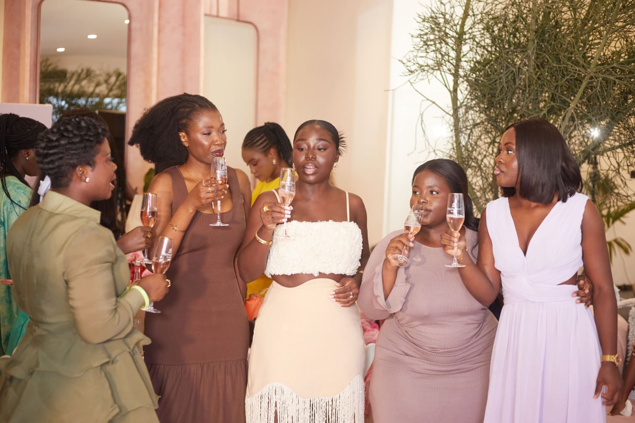 A close circle of attendees toasting with rosé in the pink-pillared room