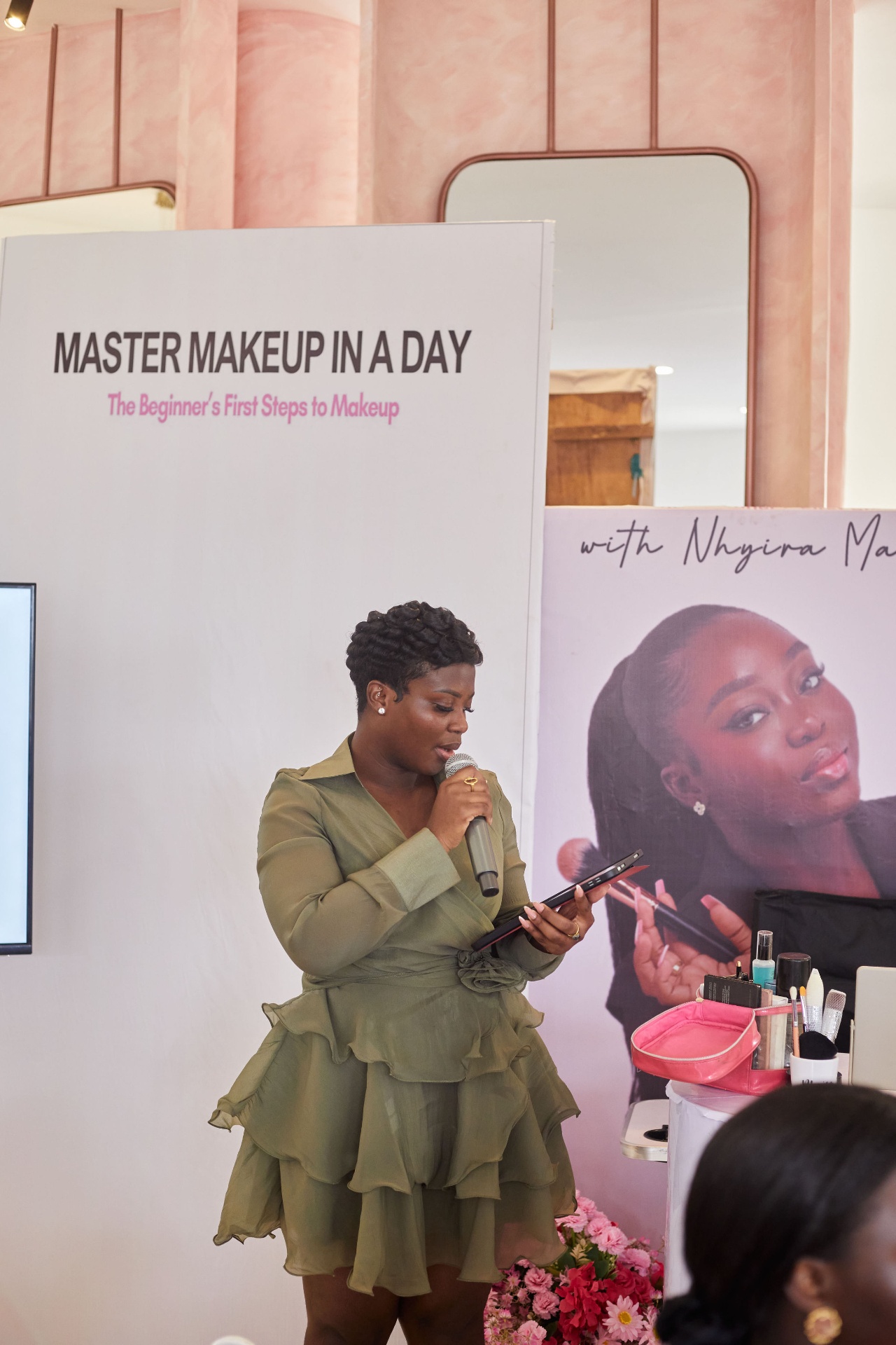 Nhyira presenting at the front of the room beside her event banners