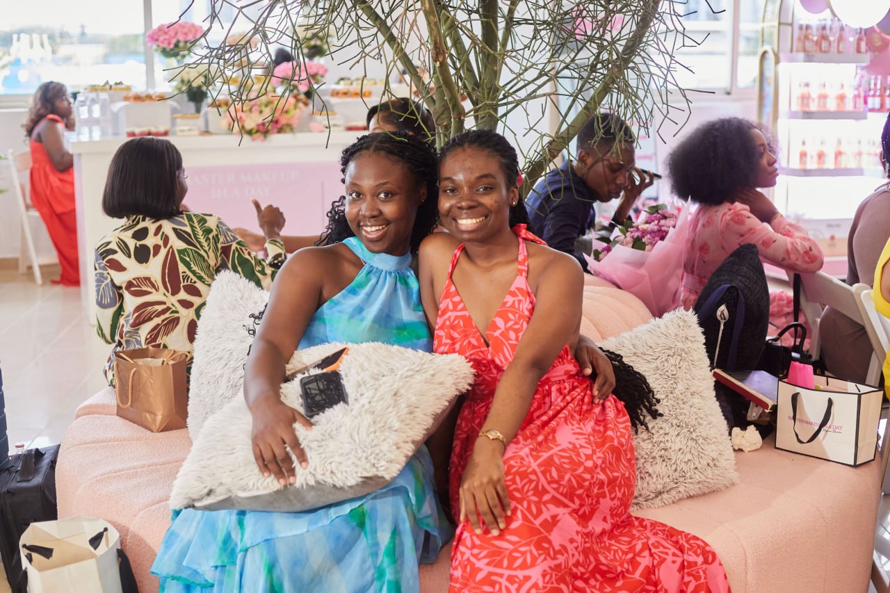 Two attendees on the pink couch under the dried branches