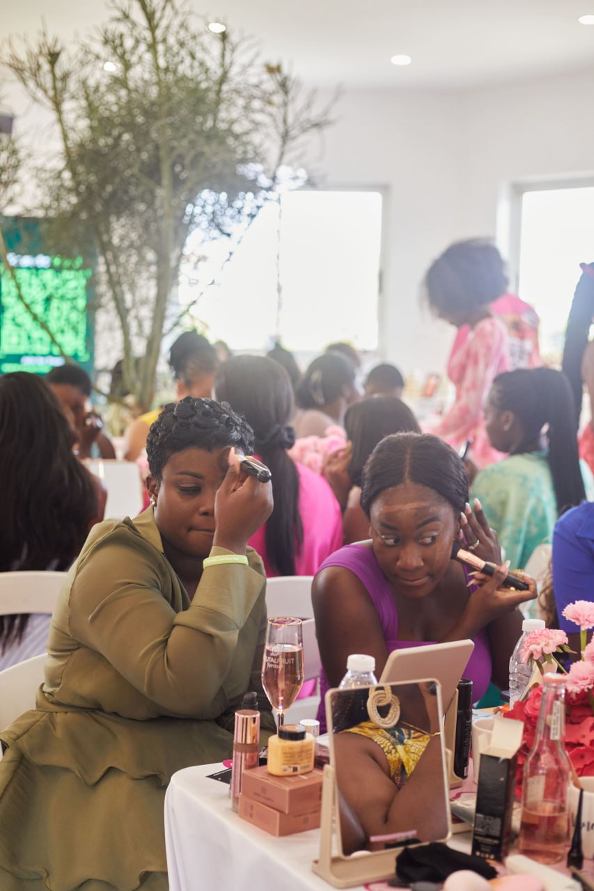 Two attendees applying makeup side by side in the busy room