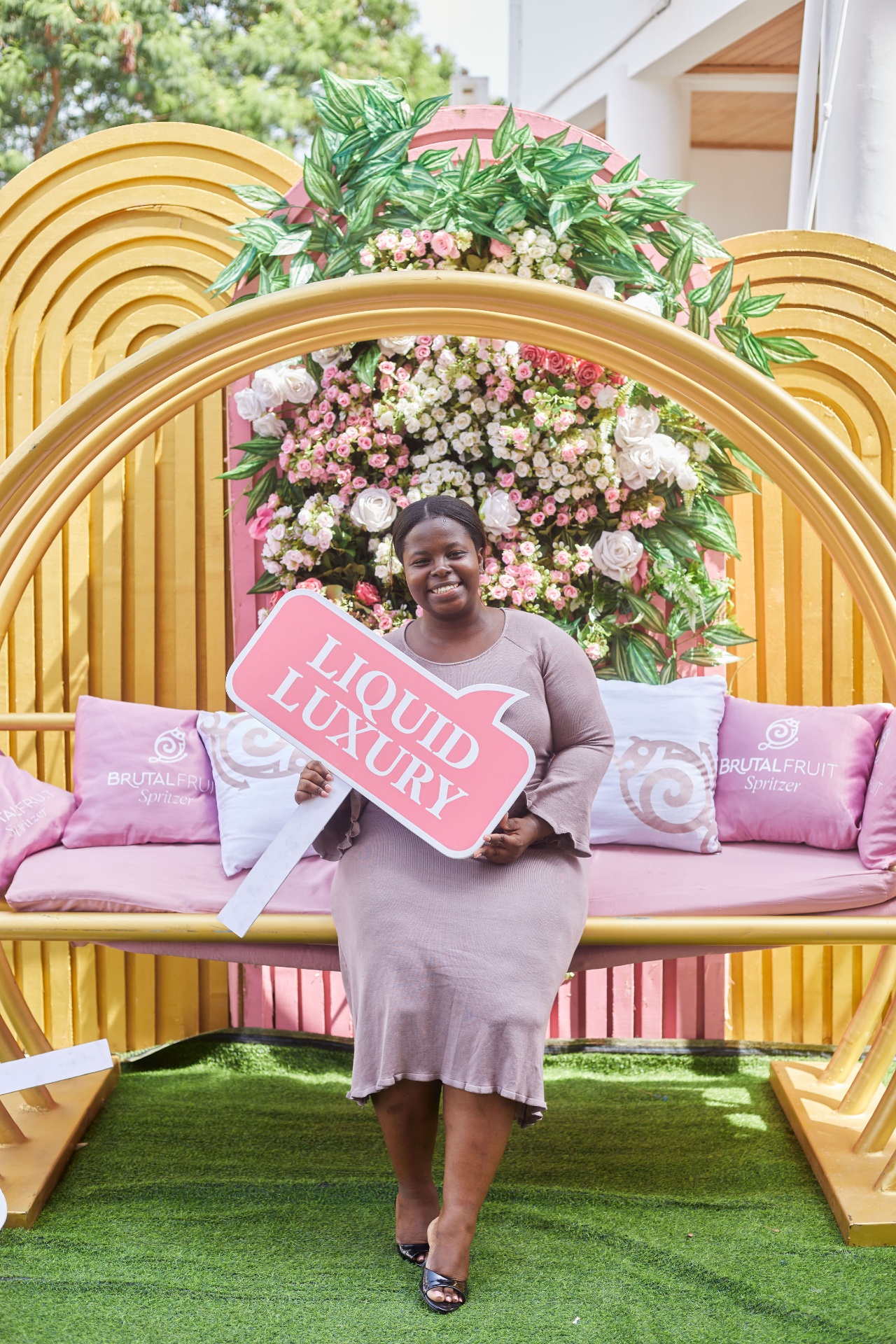 An attendee posing under the Liquid Luxury floral arch